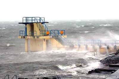 Large waves break around a diving tower on a rough sea