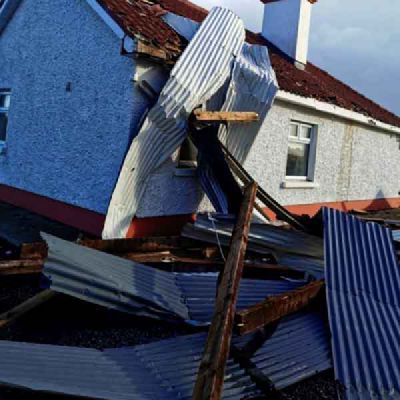 Sheets of corrugated metal and timber lie against the wall of a house