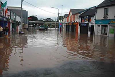Flood water fills a main street between shops and houses